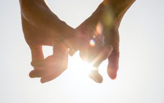 Couple holding hands toward the sun