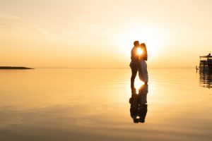 Loving couple enjoy sunset standing in shallow lake water